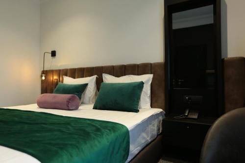 a bedroom with a bed with green and white pillows at Hotel Rubis in Ferizaj
