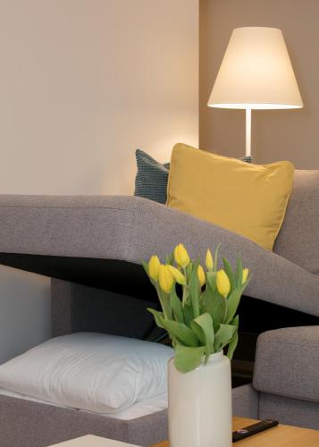 a vase of yellow tulips on a table in front of a couch at TP City Apartment - City Center in Tallinn