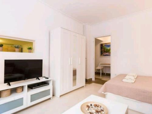 een witte woonkamer met een televisie en een bed bij Kolonaki Elegant apartment in Athene