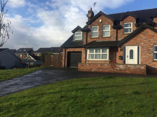 a brick house with a driveway in a yard at Glendona Lodge in Glenavy