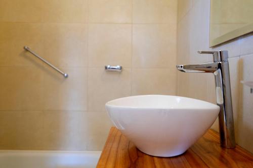 a bathroom with a white bowl sink on a wooden floor at Valeria Playa Apart in Valeria del Mar