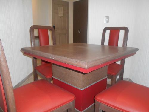a table with four chairs and a wooden table with red seats at Hotel Puente Real in Puebla