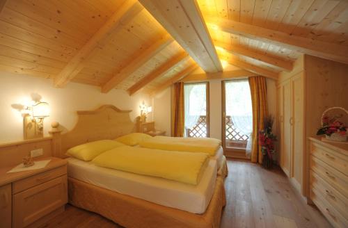 Un dormitorio con una cama grande en una habitación con techos de madera. en Romantic Chalet Dolomiti en Zoldo Alto