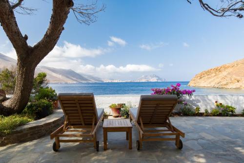 two chairs and a table next to the beach at Petradi Studios & Villa in Aegiali