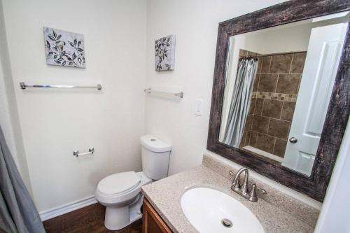 a bathroom with a toilet and a sink and a mirror at Hays St Cozy Remodeled 2BR/2BA house sleeps 8 in San Antonio