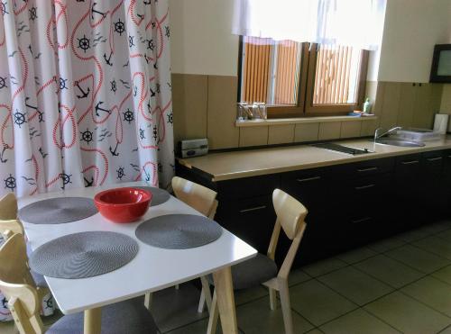 Una cocina con una mesa blanca y un cuenco rojo encima. en ApartamentyPrzyMorzu Olympic Park z Prywatnym Tarasem z Widokiem Na Morze, en Kołobrzeg