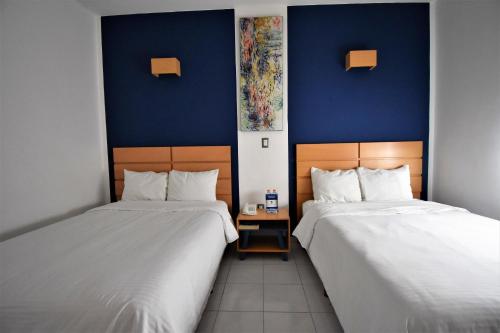 two beds in a room with blue walls at Hotel México Inn Express in Salamanca