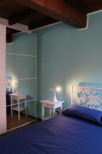 1 dormitorio azul con 1 cama y 2 mesas en La Scarana, en Ferrara