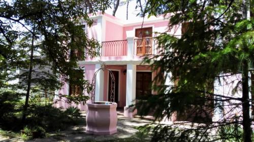 una casa rosa con balcón y árboles a marratxi en Villa Gesell