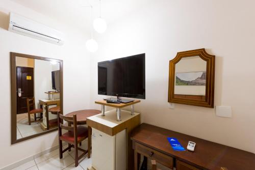 a room with a tv and a table and a mirror at Aguas do Iguaçu Hotel Centro in Foz do Iguaçu