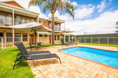 a house with a swimming pool with chairs and an umbrella at Nightcap at the Ship Inn in Busselton