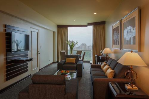 a living room with a couch and a tv at Delfines Hotel & Convention Center in Lima