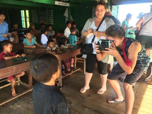 a woman taking a picture of a group of children at ST 63 Home Stay & Tour Kampong Khleang in Kâmpóng Khleăng