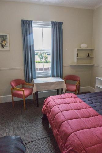 a bedroom with a bed and a table and a window at Post Office Hotel in Foxton