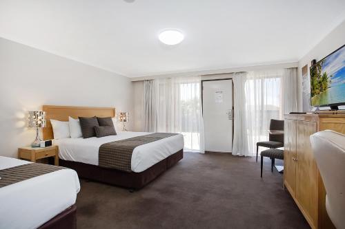 a hotel room with two beds and a flat screen tv at Mid City Motel Warrnambool in Warrnambool