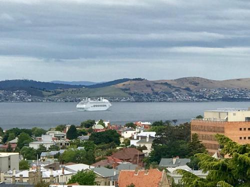 a cruise ship on the water in a city at Omaroo House - panoramic water views in Hobart