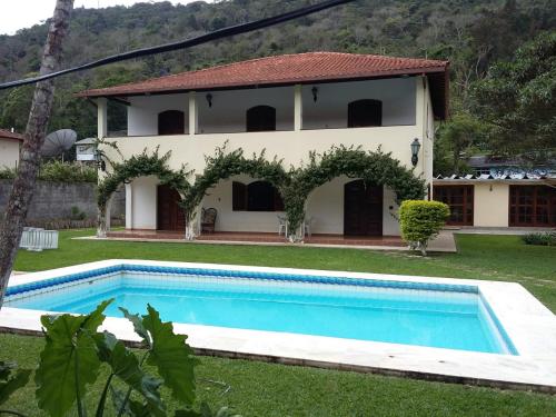 a villa with a swimming pool in front of a house at Casa Aconchegante - Circuito Teresópolis Friburgo in Teresópolis