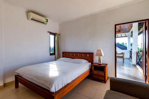 a bedroom with a bed and a chair and a mirror at Medewi Surf Villa in Pulukan