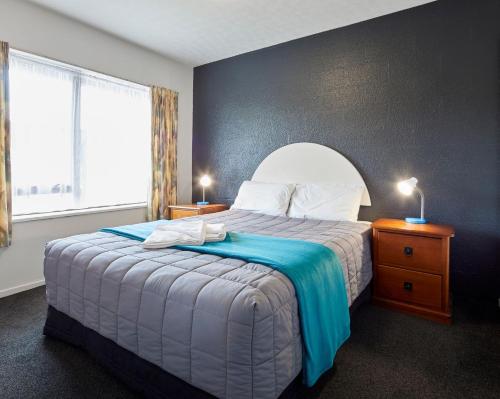 a bedroom with a large bed with a blue wall at Aotea Motel in Christchurch