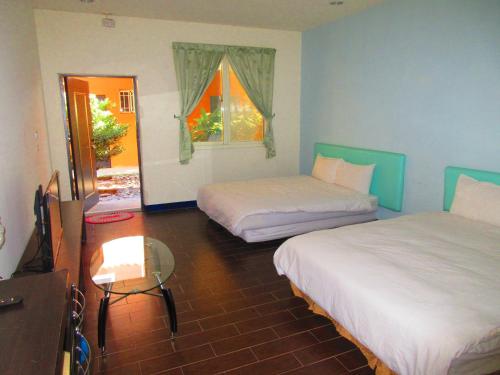 a room with two beds and a table and a window at Ivan Garden B&B in Hengchun