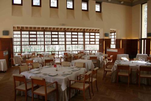 un comedor con mesas y sillas blancas y ventanas en Gran Hotel – Balneario de Panticosa en Panticosa