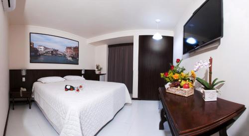 a bedroom with a bed and a table and a tv at Aguas do Iguaçu Hotel Centro in Foz do Iguaçu