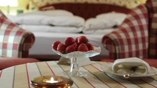 a table with a bowl of strawberries on a table at Hotel Chalet Del Sogno in Madonna di Campiglio