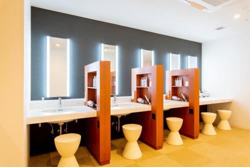 a bathroom with three sinks and three mirrors at First Cabin Ichigaya in Tokyo