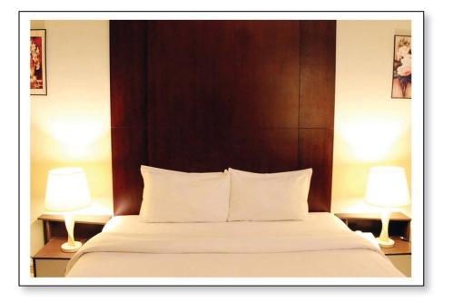 a bedroom with a large bed with two lamps at Ginasuite Hotel in Bandar Seri Begawan