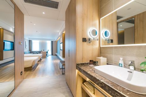 a bathroom with a sink and a bed in a room at Atour Hotel (Nanjing Xingang Development Area) in Nanjing