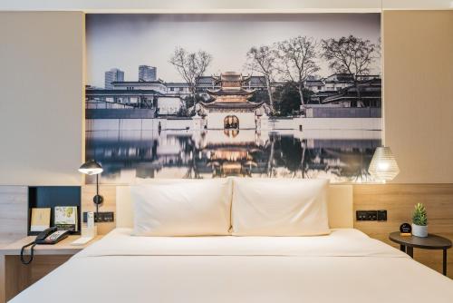 a bedroom with a bed with a painting on the wall at Atour Hotel (Nanjing Xingang Development Area) in Nanjing
