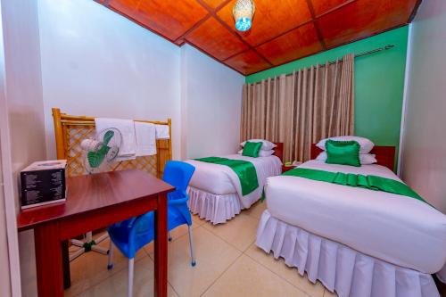 Cette chambre comprend deux lits, une table et un bureau. dans l'établissement B.Maurice Guest House, à Kigali
