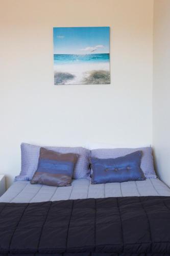 a bed with blue pillows and a picture on the wall at Post Office Hotel in Foxton