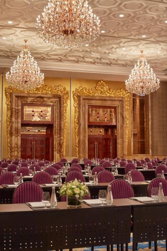a dining room with purple chairs and tables and chandeliers at The Reverie Saigon Residential Suites in Ho Chi Minh City