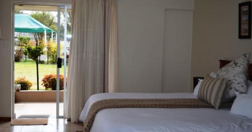 MatatieleにあるDe Berg Guesthouseのベッドルーム1室(ベッド1台付)、スライド式ガラスドアが備わります。
