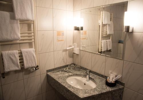 a bathroom with a sink and a mirror and towels at Hotel Hellers Krug in Holzminden
