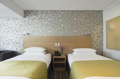 a hotel room with two beds and a window at Nine Tree Hotel Myeongdong in Seoul