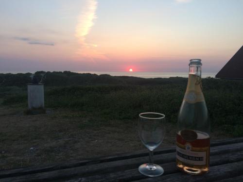 a bottle of wine and a glass on a table with the sunset at Luksus i Løkken in Løkken