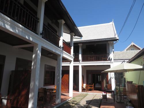 an outside view of a building with tables and an umbrella at QUEEN'S HOUSE in Luang Prabang