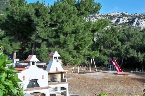 a park with a playground with a slide and trees at Miraluna Aparthotel in Lefkos Karpathou