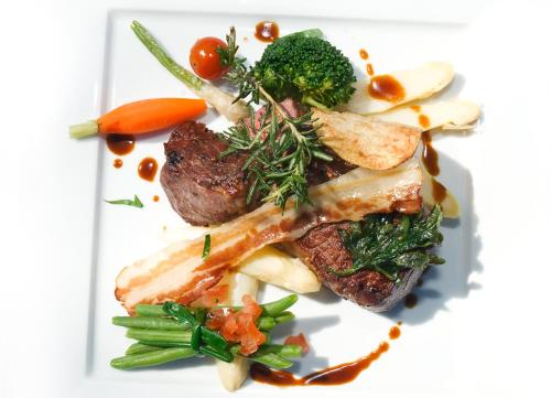 a white plate of food with meat and vegetables at Landgasthof Kasch - Hotel und Restaurant in Malente