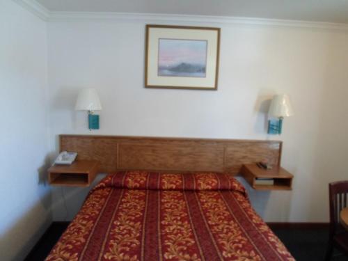 a hotel room with a bed and two night stands at Economy Inn Morgan Hill in Morgan Hill