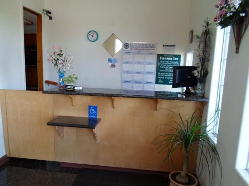 a cashier counter in a waiting room with a plant at Economy Inn Morgan Hill in Morgan Hill