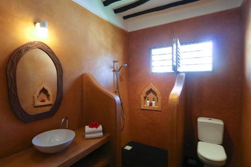 ein Bad mit einem Waschbecken und einem Spiegel in der Unterkunft Blue Oyster Hotel in Jambiani