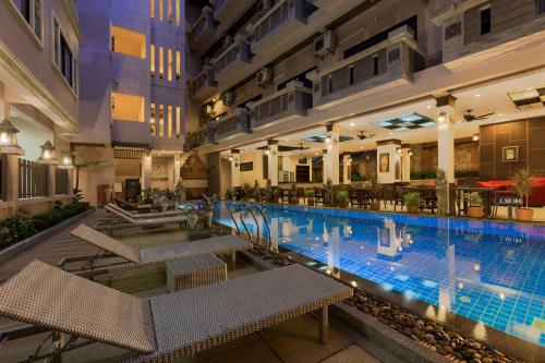 a large swimming pool in a building with tables and chairs at Seeka Boutique Resort - Relaxing Stay - Balcony, Pool & Near Beach in Patong Beach
