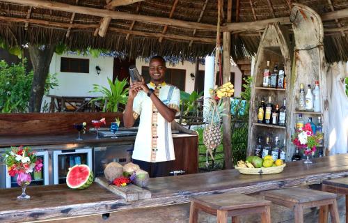 a man taking a picture of a bar at Blue Oyster Hotel in Jambiani