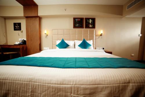 a bedroom with a large bed with blue pillows at YASH INTERNATIONAL in Kozhikode