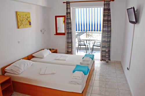 a room with two beds and a balcony at Vicky Studios in Myrina