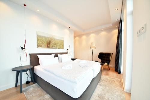 a bedroom with a large white bed and a chair at Luxus Apartment MeerFreude in Ostseebad Sellin