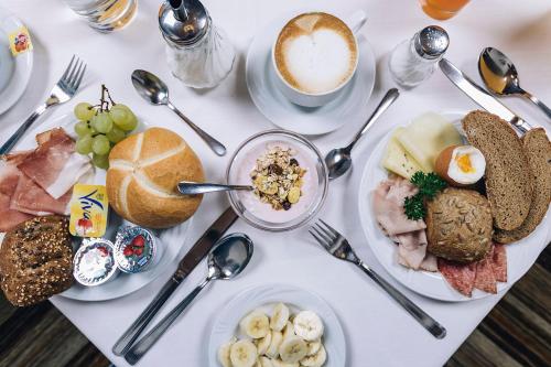a white table topped with plates of food and a cup of coffee at Hotel Schönwies in Trodena